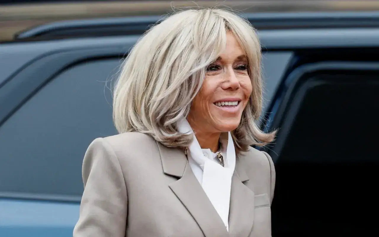 Brigitte Macron z uśmiechem, jej charakterystyczne blond włosy lekko falują.
