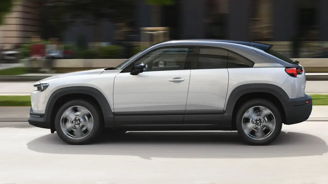 El Mazda MX-30, un coche el&eacute;ctrico con un dise&ntilde;o moderno, se desplaza por la ciudad. Sus medidas son ideales para el entorno urbano.