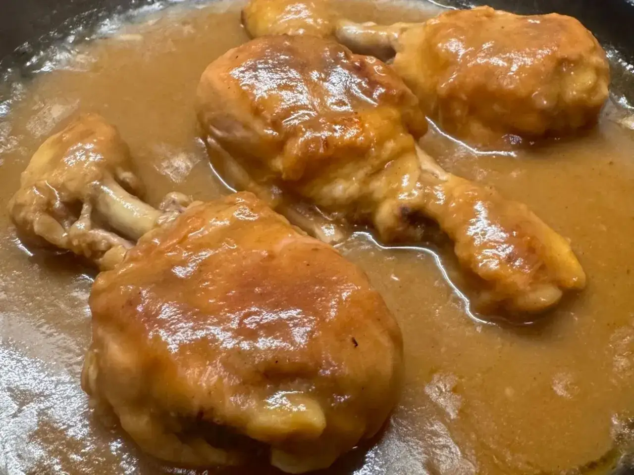 Cosce di pollo succulente immerse in una salsa densa e dorata, un delizioso pollo alla birra pronto per essere gustato.