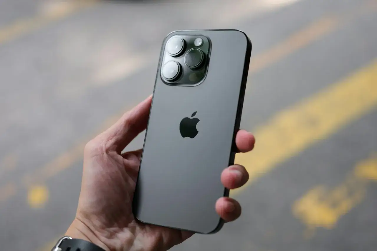 Dłoń trzyma szary iPhone z trzema obiektywami aparatu. Zastanawiasz się, jaki iPhone jest najlepszy? Ten model wygląda obiecująco.