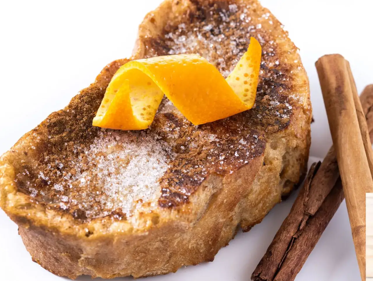Torrijas caseras, esponjosas y doradas, espolvoreadas con azúcar y canela, decoradas con piel de naranja. ¡Una delicia para tu receta!