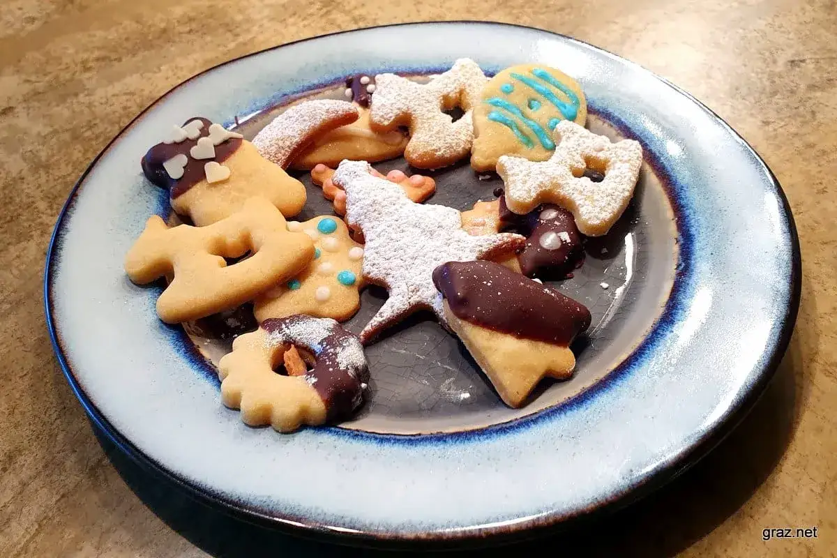 Ein Teller voller selbstgemachter Butterkekse, verziert mit Schokolade, Puderzucker und blauer Glasur. Ein tolles Rezept für Butterkekse!