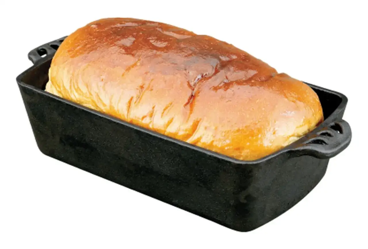 Ein goldbraunes Brot ruht in einer schwarzen Gusseisenform, perfekt zum Brot backen.