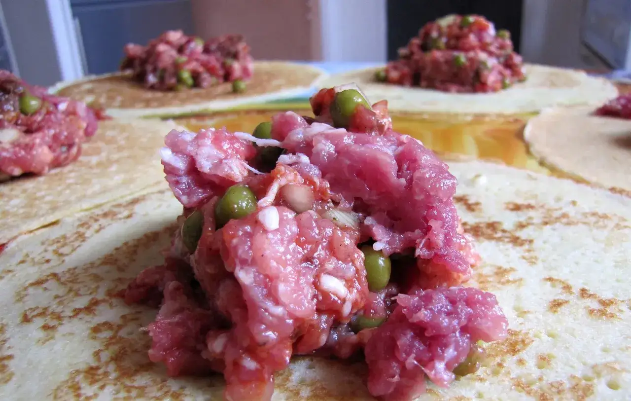 Naleśniki z mięsem i groszkiem, przygotowywane do zawinięcia, przypominają farszem cannelloni.