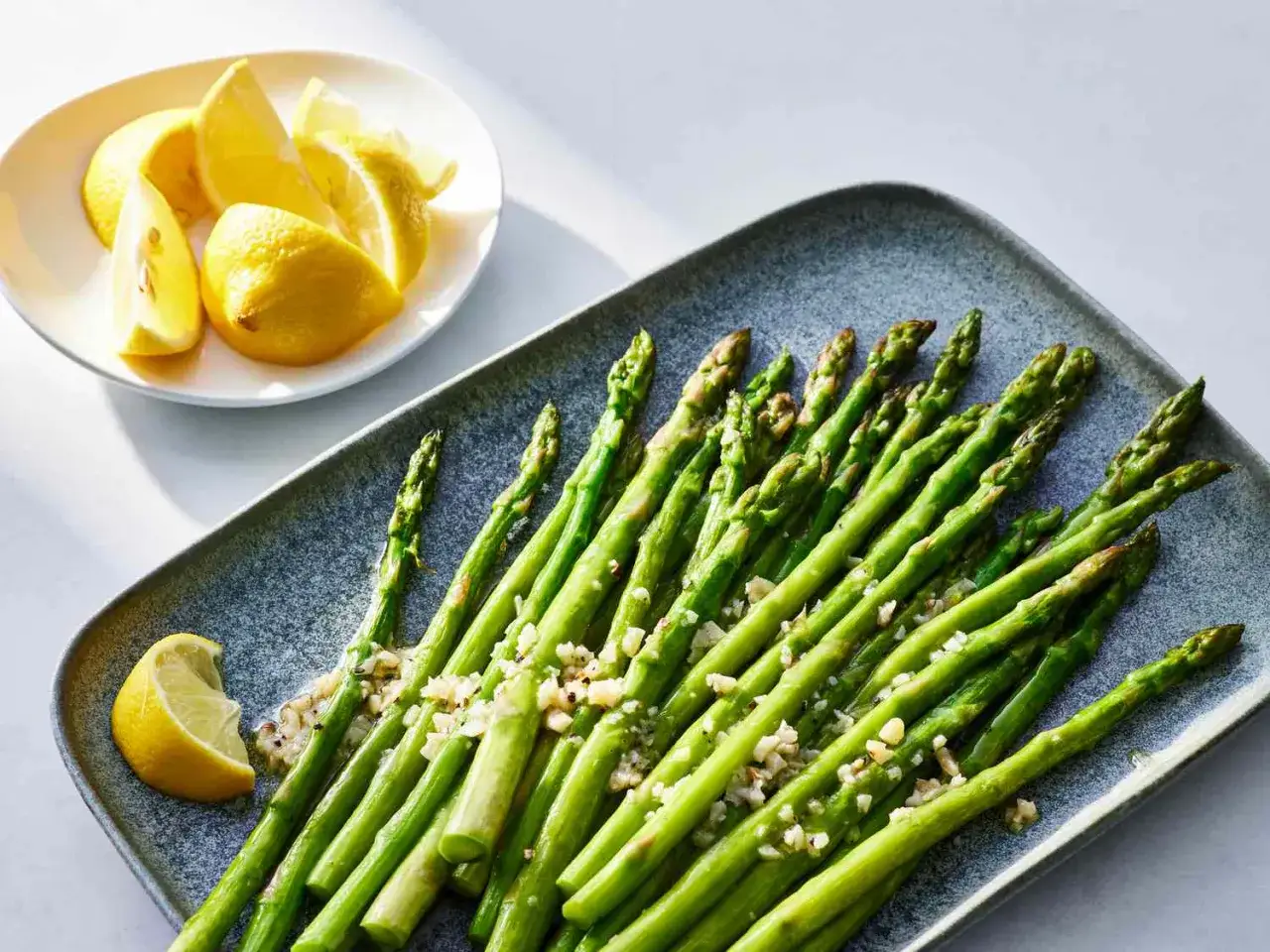 Espárragos verdes tiernos con ajo picado y rodajas de limón fresco, listos para disfrutar.