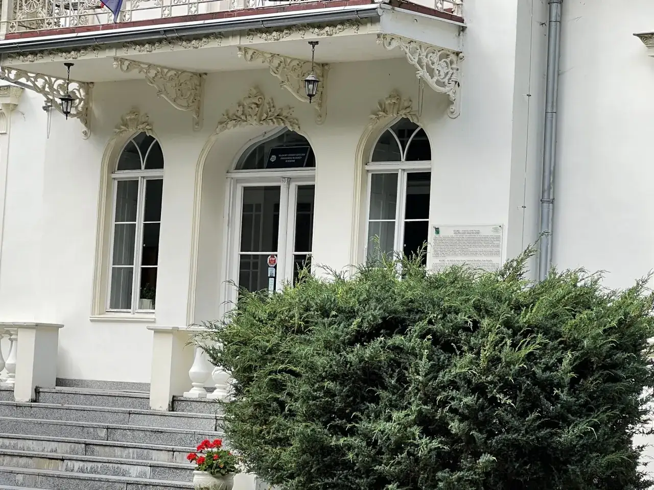 Elegancki pałac w Nosowie z ozdobnym gankiem i schodami. Krzewy i kwiaty dodają uroku.