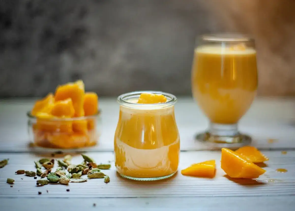 Deser z mango lassi i mus z marakui, ozdobione kawałkami owoców i kardamonem.
