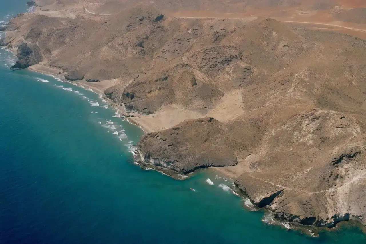 Vista aérea de la cala Príncipe en Cabo de Gata, con aguas turquesas y montañas áridas.