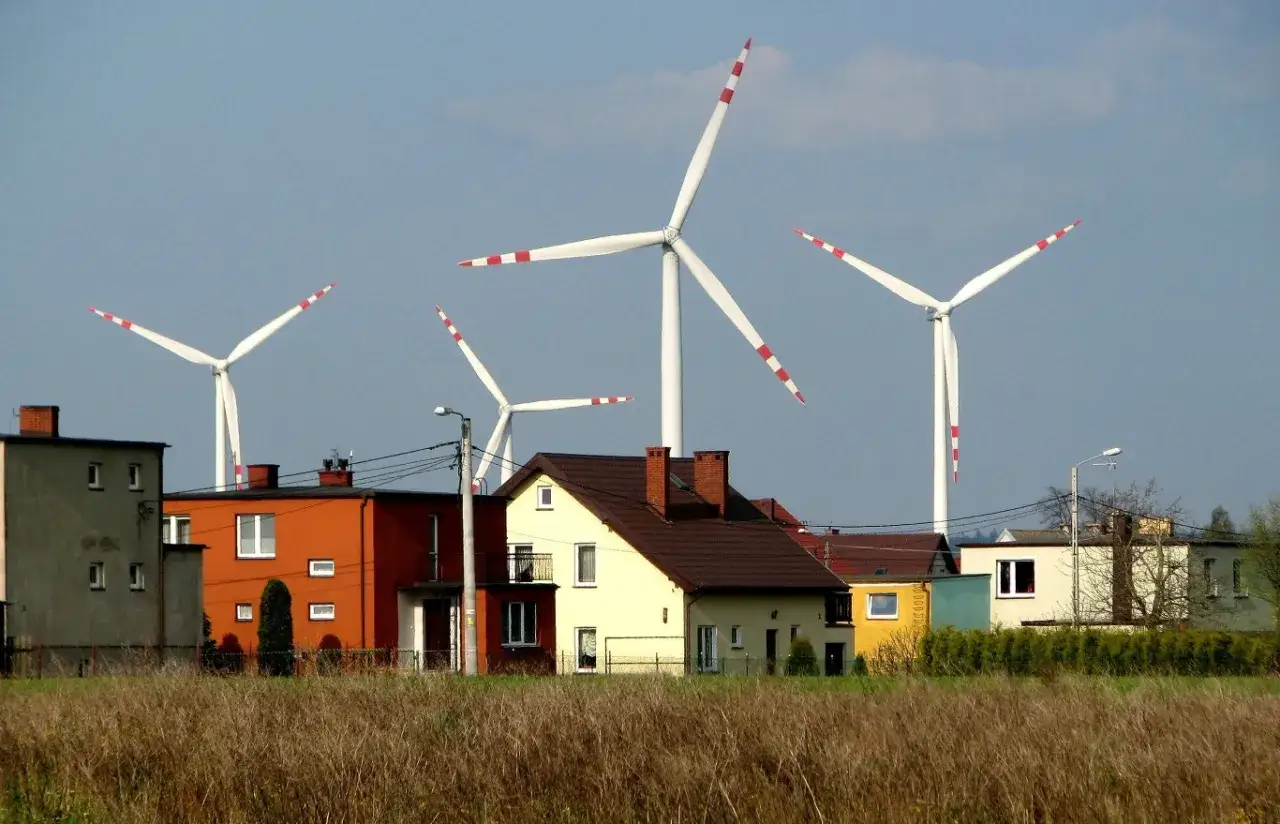 Wysokość wiatraków robi wrażenie na tle kolorowych domów i nieba.