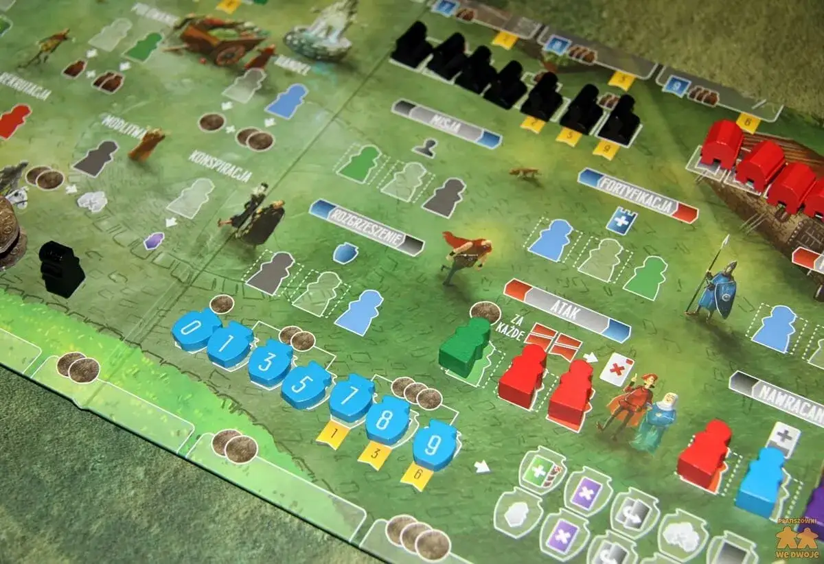 Paladyni zachodniego kr&oacute;lestwa przygotowują się do bitwy na planszy gry. Czerwone i niebieskie pionki symbolizują wojska, a pola akcji wskazują na rekrutację, modlitwę i atak.
