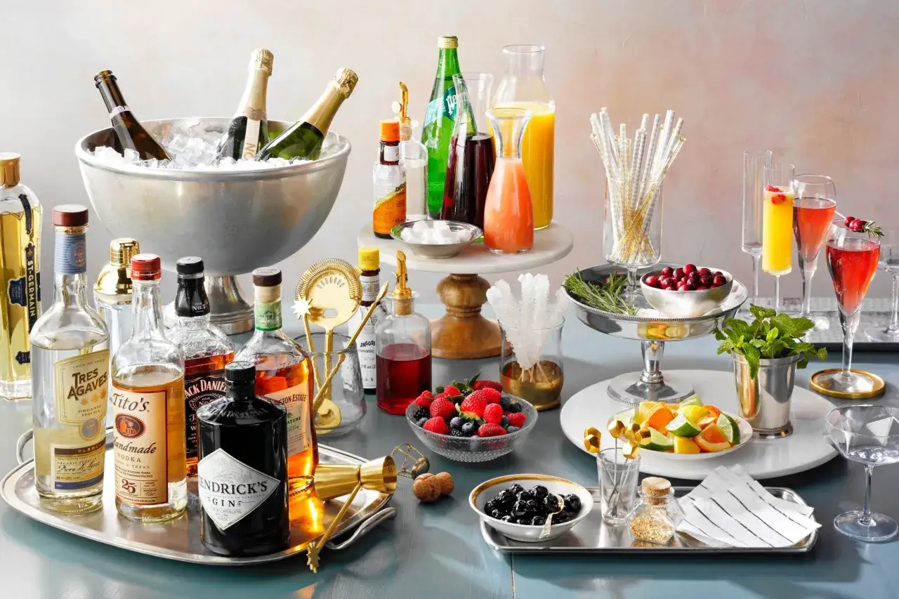 Prosecco a Szampan w koktajlach, obok butelki alkoholi, owoców i akcesoriów barmańskich. Idealne na przyjęcie!