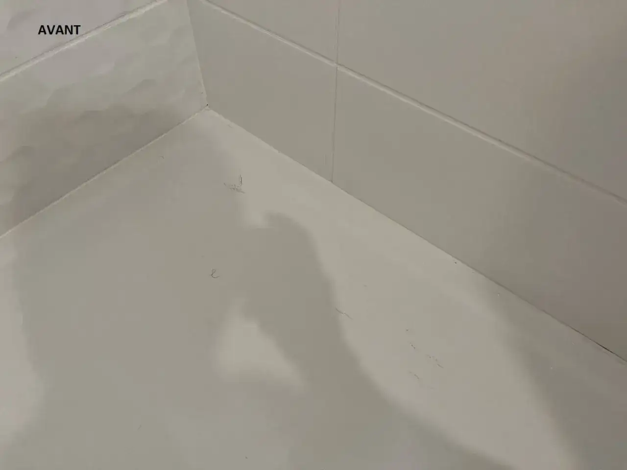 Coin de baignoire en acrylique avant réparation, montrant une légère rayure sur la surface blanche.
