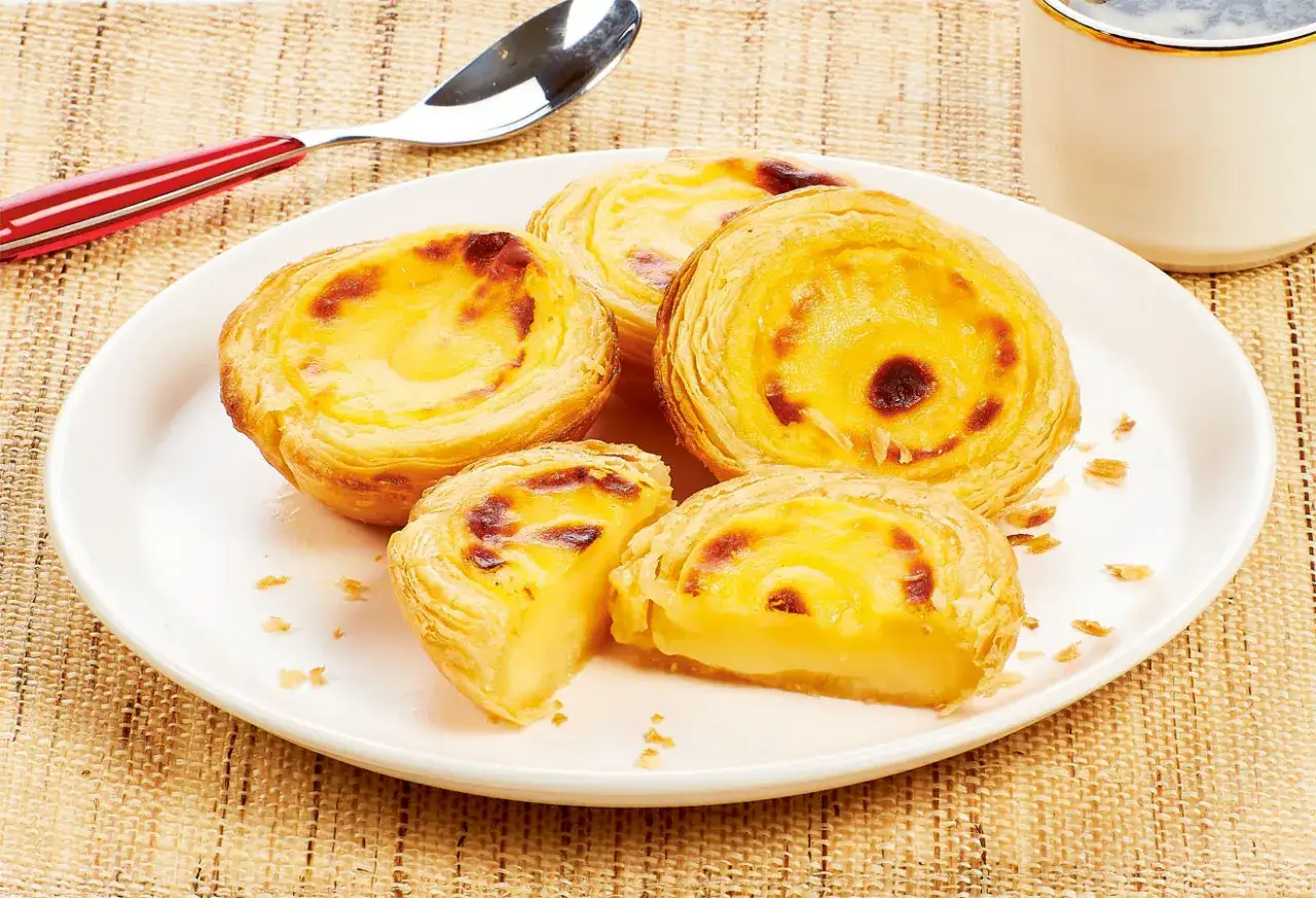 Délicieux pasteis de nata sur une assiette blanche, prêts à être dégustés. Une recette à essayer !