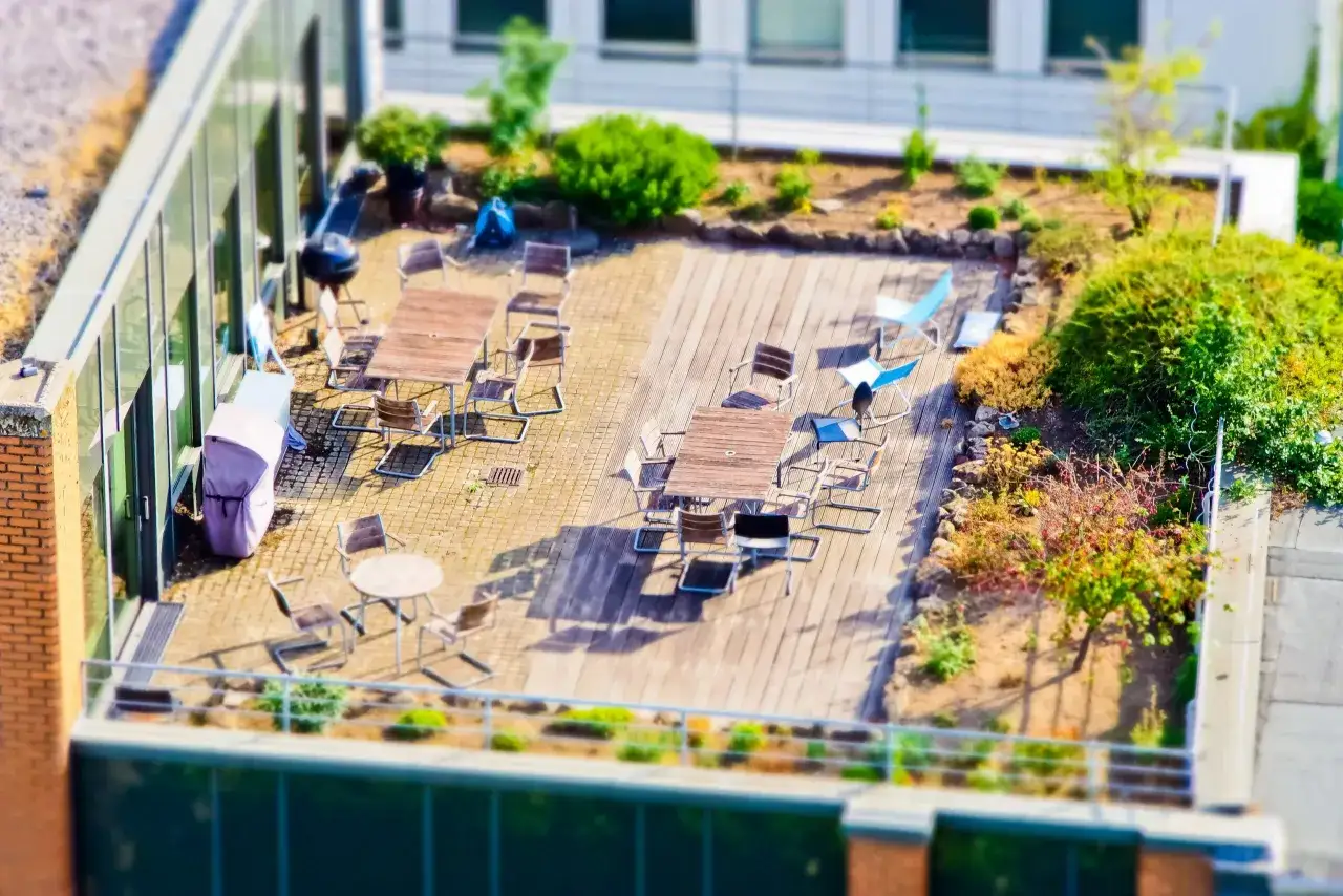 Gemütliche Dachterrasse mit Tischen, Stühlen, Grill und Grünflächen. Die traglast der Dachterrasse scheint für entspannte Stunden ausgelegt zu sein.