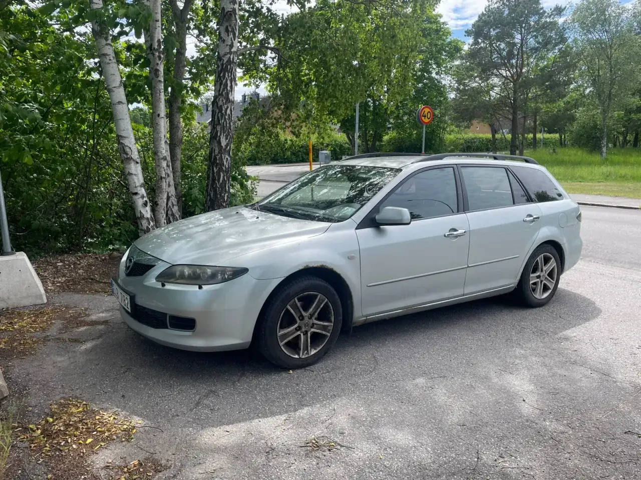 Silver Mazda 6 kombi parkerad vid en v&auml;g, med rostfl&auml;ckar som indikerar ett Mazda 6 problem.