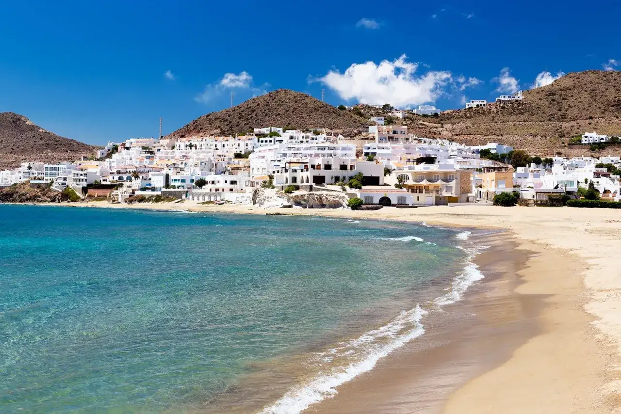 Pueblo blanco en la costa, con playa dorada y mar turquesa. Un lugar idílico que ver en Cabo de Gata.