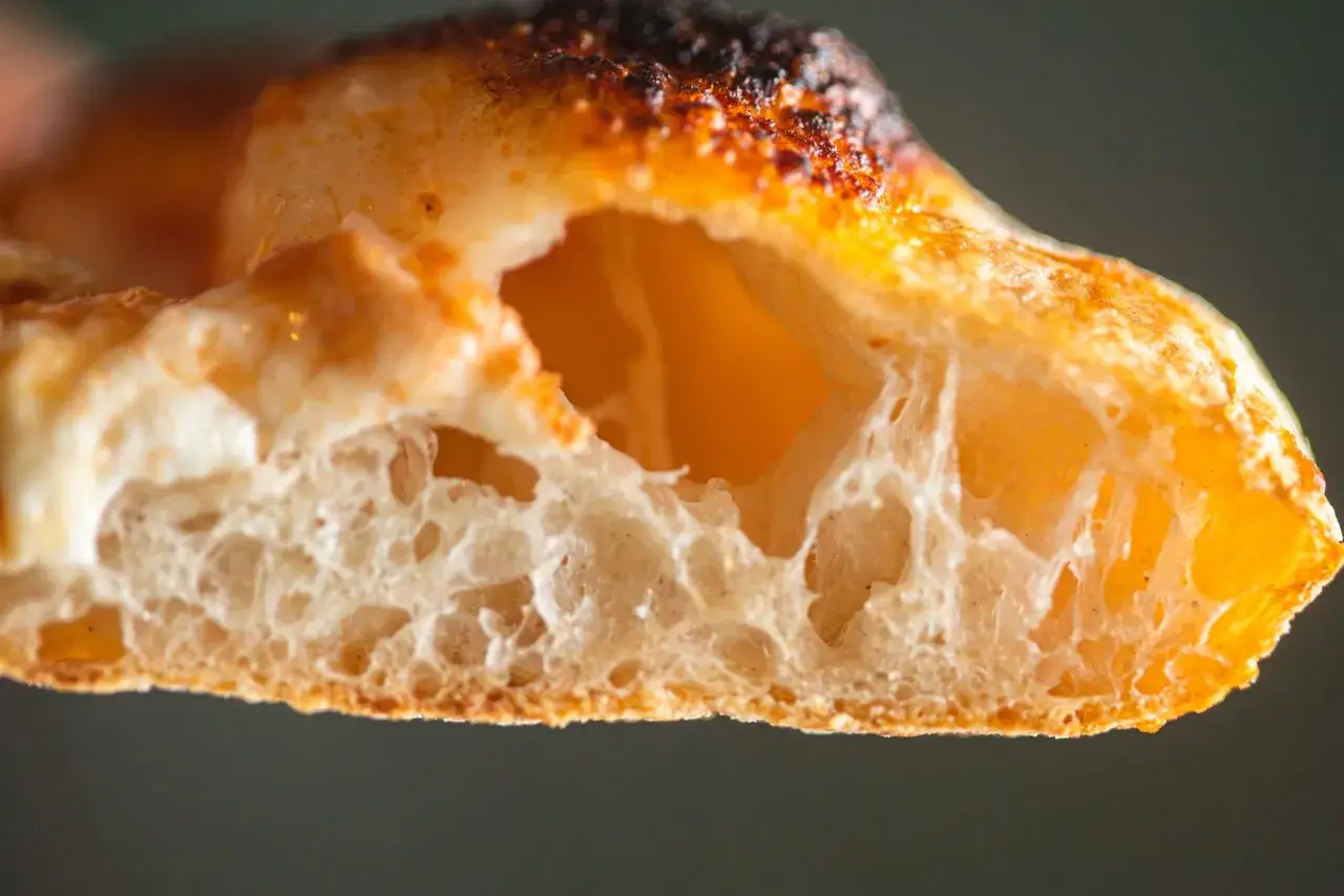 La pizza lievitazione 24 ore mostra una crosta alveolata e dorata, con un interno soffice e arioso.