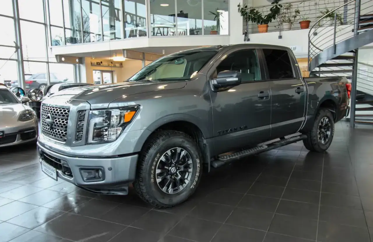 Szary Nissan Titan V8 z czarnymi felgami stoi w salonie samochodowym.