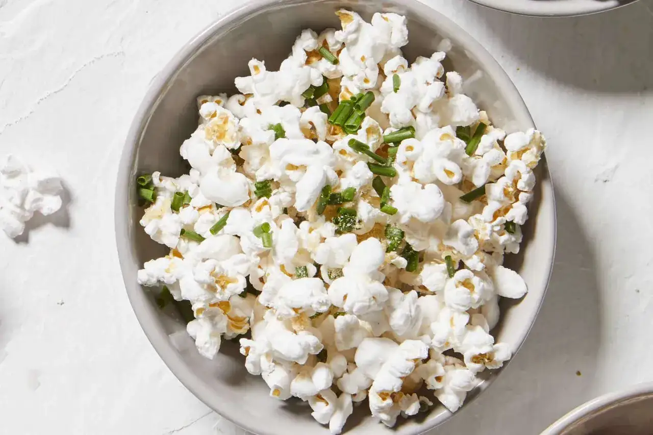 Misternie przygotowany popcorn z zielonym szczypiorkiem w misce. Czy popcorn tuczy? Zależy od dodatków!