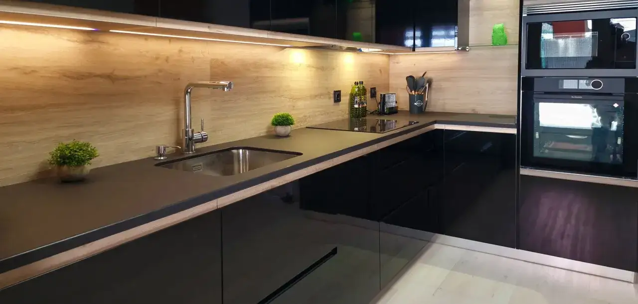 Cocinas negras y madera: encimera oscura, fregadero de acero inoxidable, grifo cromado y electrodomésticos integrados.