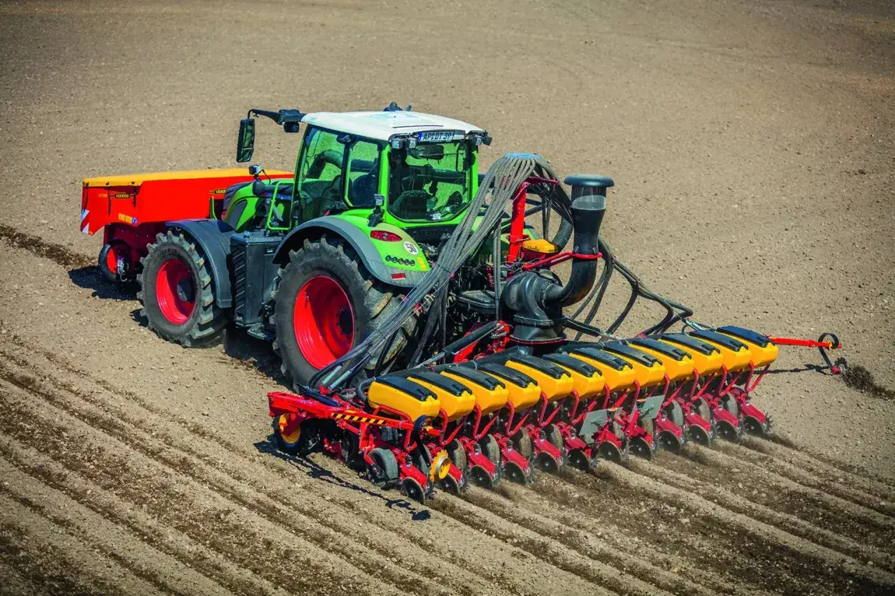 Zielony traktor z siewnikiem precyzyjnym wykonuje wysiew soi na 1 ha. Maszyna r&oacute;wnomiernie rozsiewa nasiona w przygotowane bruzdy.