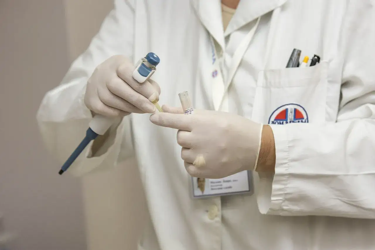Laborant w białym fartuchu, rękawiczkach, pobiera próbkę do analizy. To kluczowy etap w procesie obdukcji.