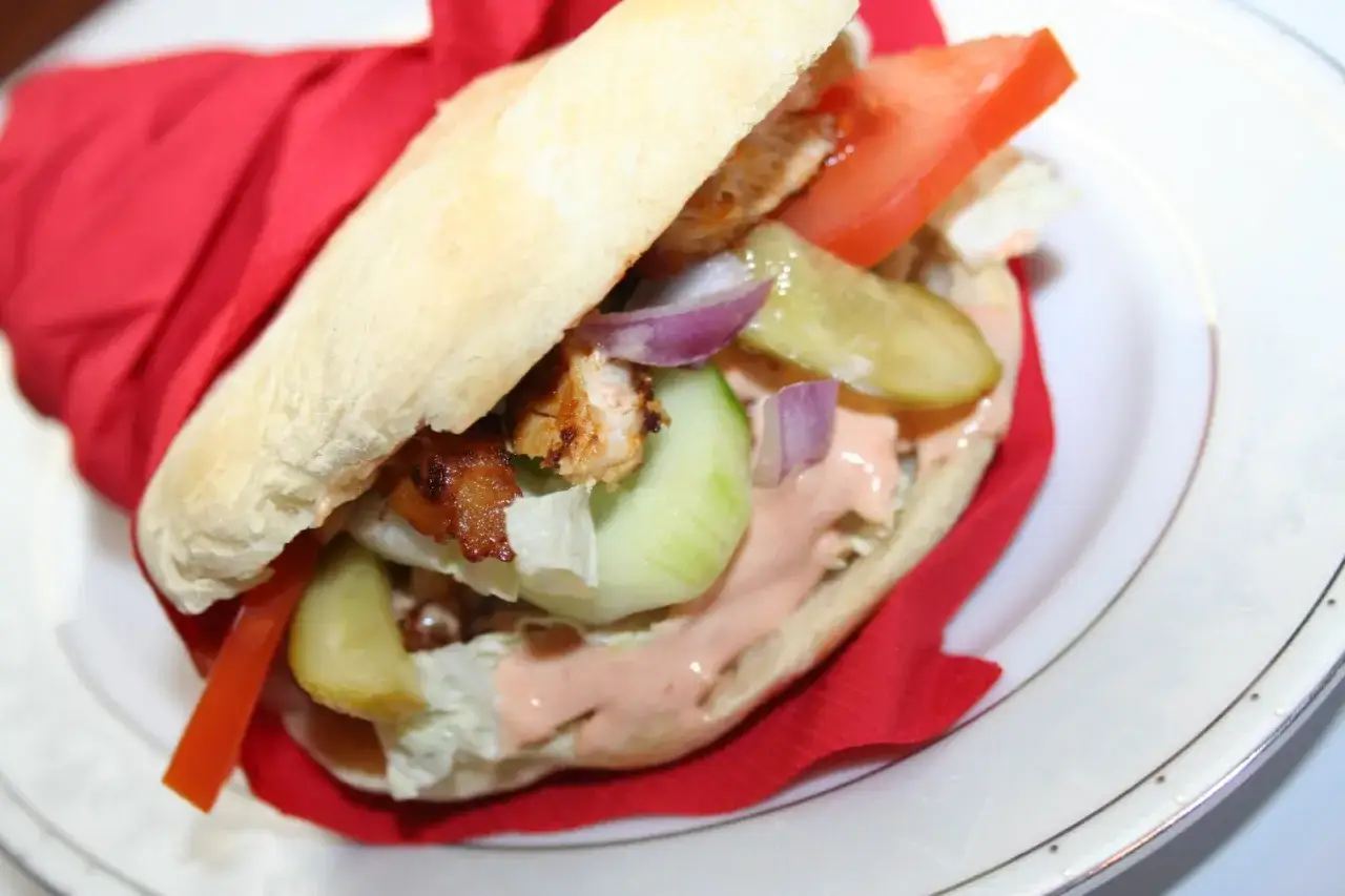 Pyszny kebab z kurczakiem, warzywami i kremowym sosem do kebaba, zawinięty w czerwoną serwetkę.