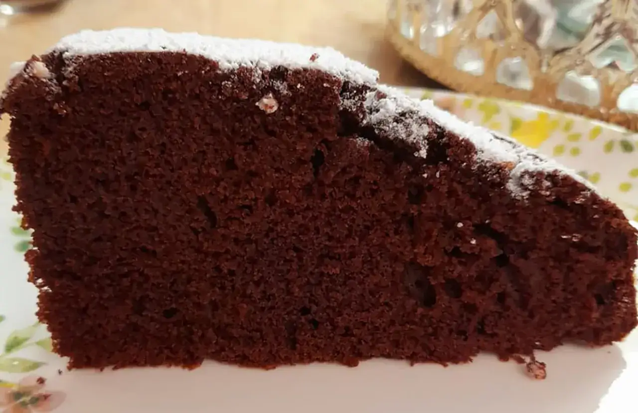 Una fetta di torta al cioccolato, soffice e umida, cosparsa di zucchero a velo. Perfetta per chi ama il gusto intenso della torta mascarpone e cioccolato.