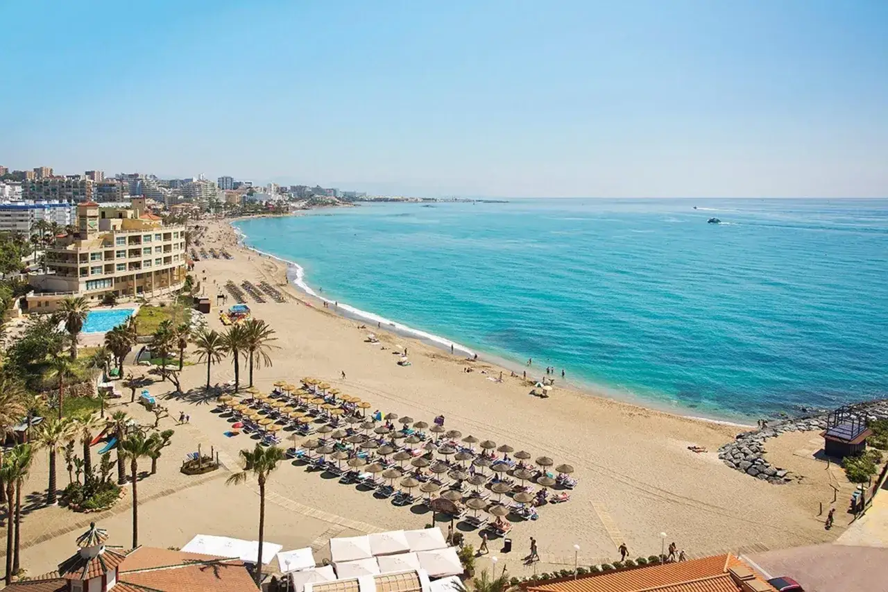 Słoneczna piaszczysta plaża na Costa del Sol z palmami i turkusową wodą