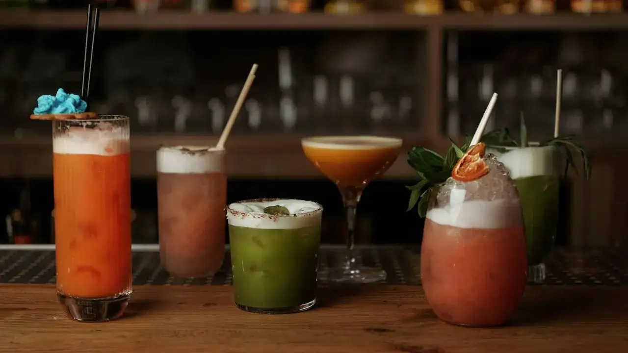 Klarowanie smaków: pięć kolorowych drinków z pianką i dekoracjami na barze.