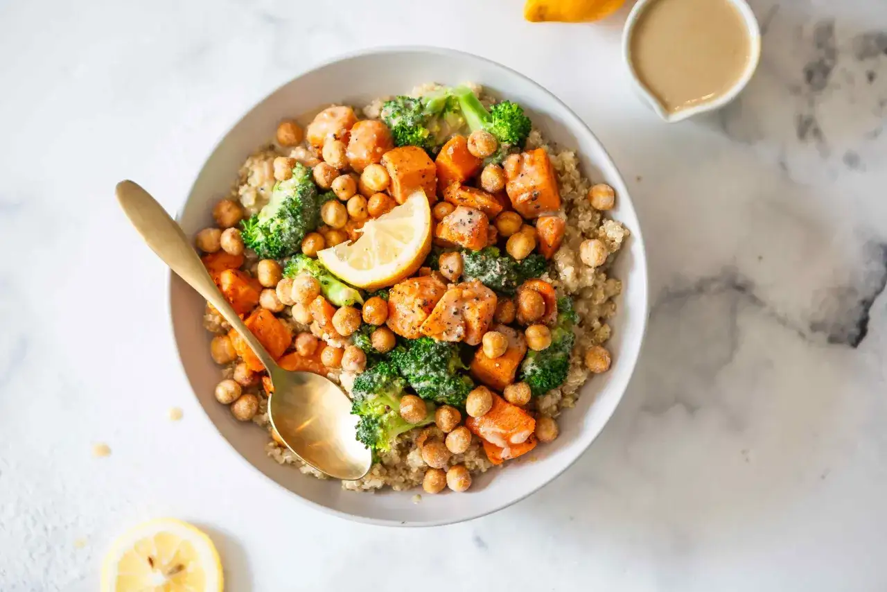 Bol de quinoa, patates douces, brocolis et pois chiches, garni de citron. Une alimentation idéale pour la récupération sportive.
