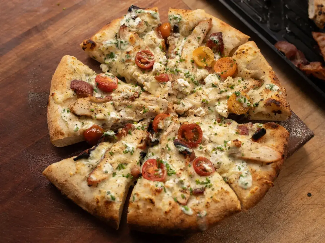 En saftig pizza med kyckling och bacon, toppad med k&ouml;rsb&auml;rstomater och kr&auml;mig ost. En riktig smakupplevelse!