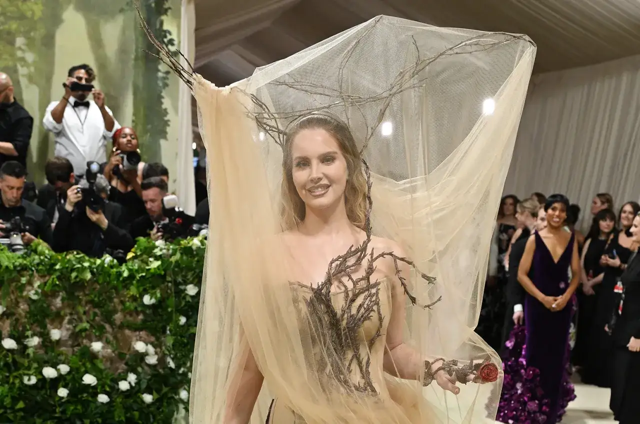 Lana Del Rey at the Met Gala, adorned in a ethereal gown with branches and a veil, captivating photographers.