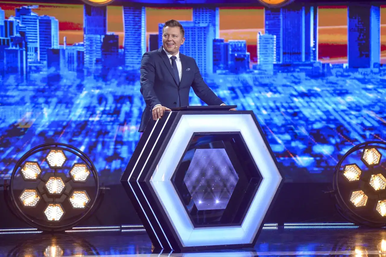 Rafał Brzozowski w garniturze na scenie programu