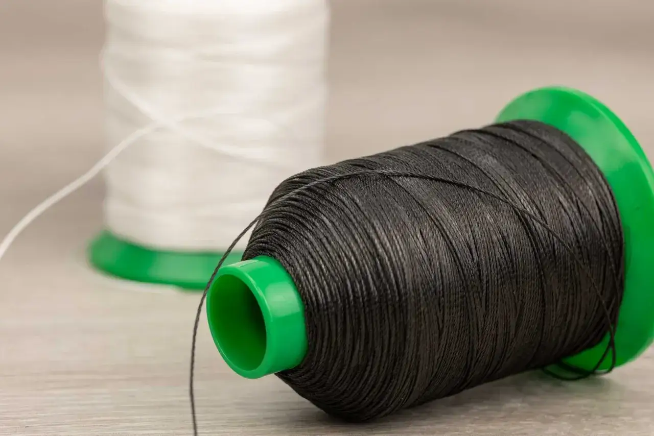 Bobina de hilo negro, lista para coser. Detr&aacute;s, otra bobina de hilo blanco. &iexcl;Qu&eacute; hilo de hilo!