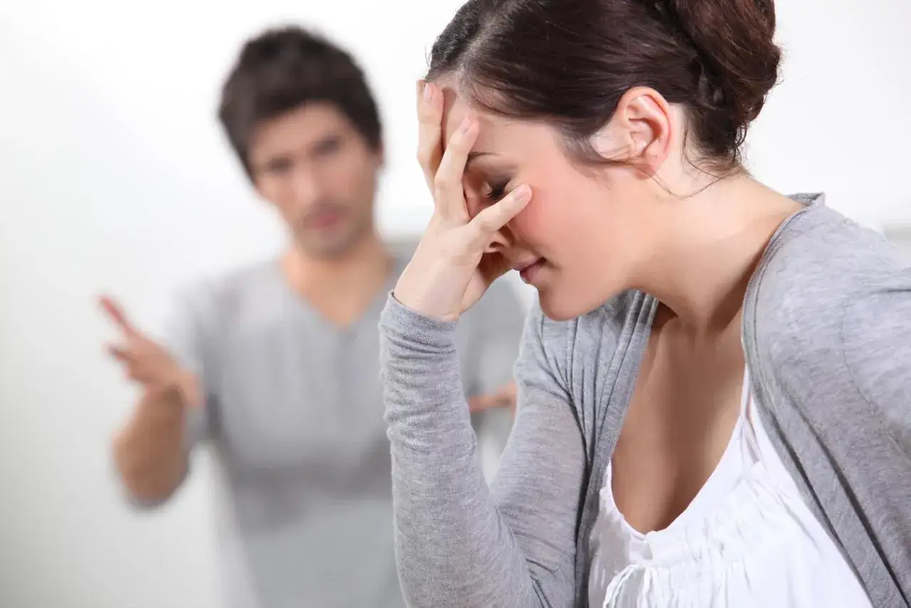 Une femme d&eacute;sesp&eacute;r&eacute;e se tient la t&ecirc;te, tandis qu'un homme lui parle avec agitation. La sc&egrave;ne &eacute;voque la tension d'une convention d'indivision lors d'un divorce.