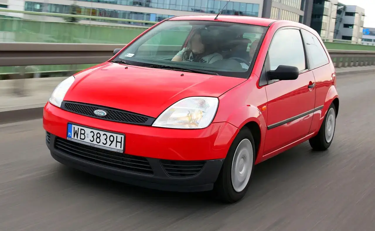 Czerwony Ford Fiesta MK6 jedzie po drodze.