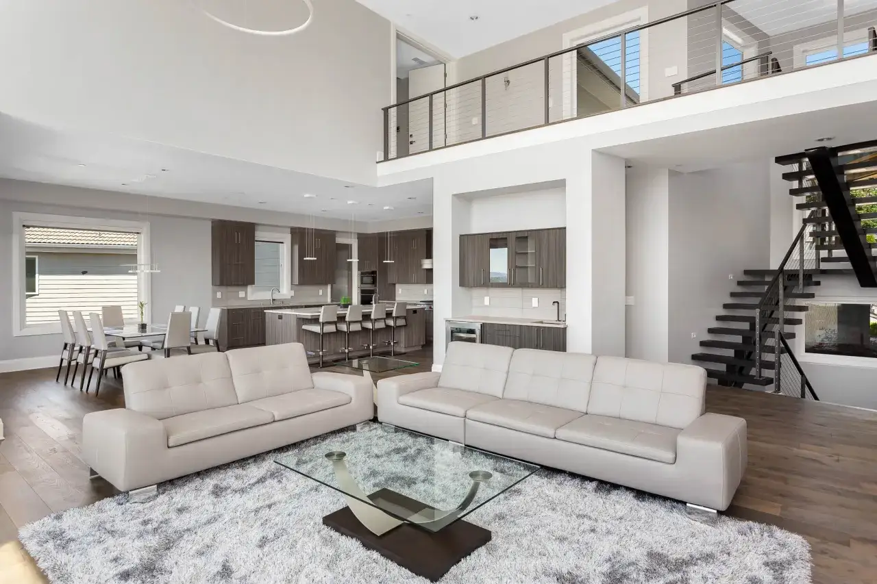 Spacious modern living room with a kitchen and dining area, captured with a real estate photography lens to showcase the open layout and luxurious finishes.