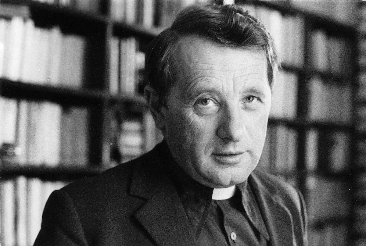 Portret księdza Józefa Tischnera, filozofa, którego **józef tischner cytaty** inspirują do myślenia. W tle regały pełne książek.