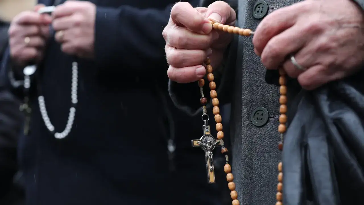 Dłoń trzyma paciorki różańca, symbolizując modlitwę do anioła stróża za dorosłe dzieci.