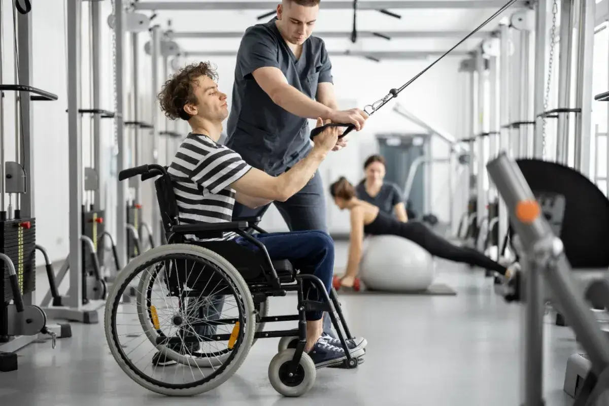 Rehabilitacja w **stopniu umiarkowanym co się należy 2026**. Mężczyzna na wózku ćwiczy z fizjoterapeutą.