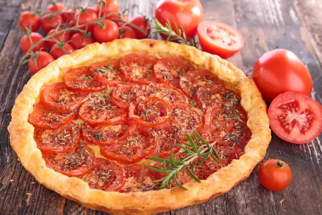 Tarte aux tomates fraîches, une recette d'été parfaite. Des tomates rouges et des herbes sur une pâte dorée.