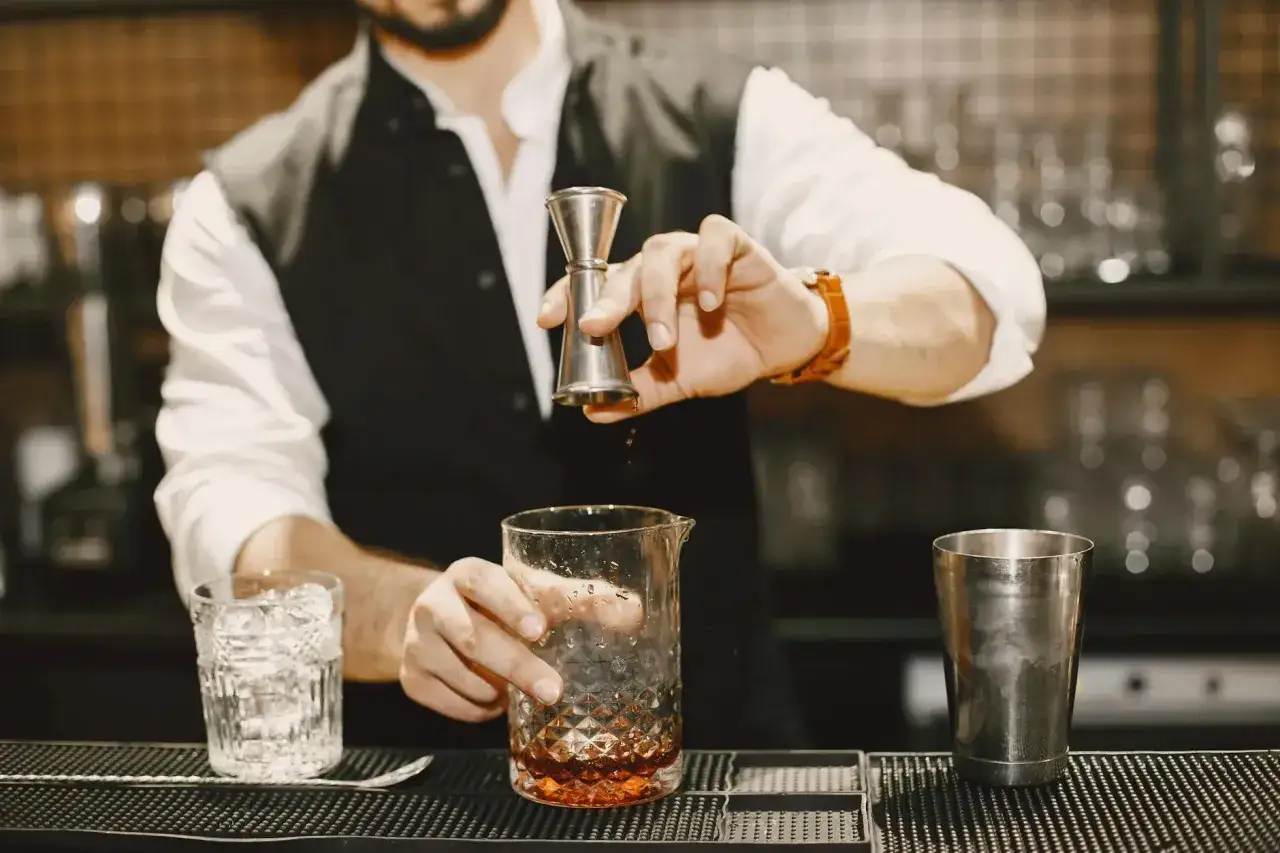 Barman dodaje składniki do szklanicy, by uniknąć mętnienia drinków typu stirred przy zbyt długim mieszaniu.