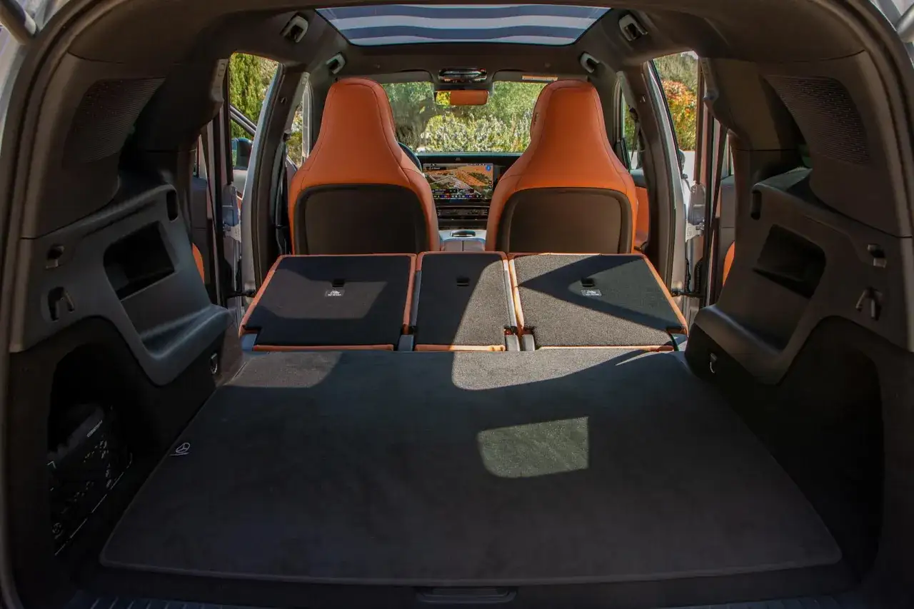 Bagageutrymmet i en Mercedes GLB testbil med f&auml;llda baks&auml;ten och orangea l&auml;ders&auml;ten framtill.