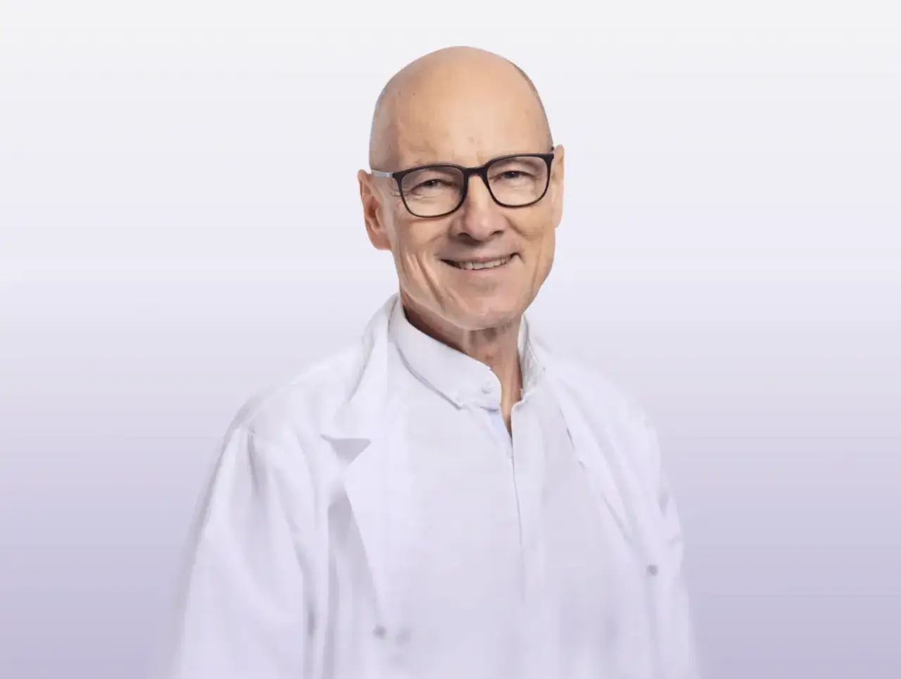 Uśmiechnięty dr Tadeusz Oleszczuk w białym kitlu i okularach.