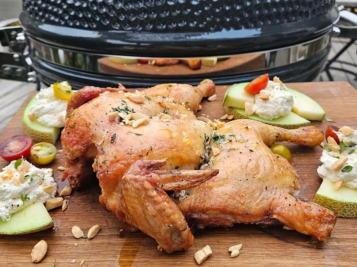 Helstekt kyckling på en skärbräda, redo att serveras. Perfekt resultat från gasolgrill med rätt temperatur.