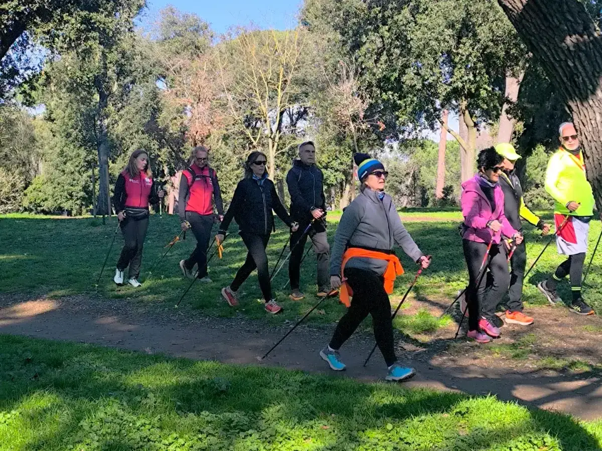 Gruppo di persone pratica nordic walking in un parco, un ottimo modo per aumentare le calorie bruciate camminando.