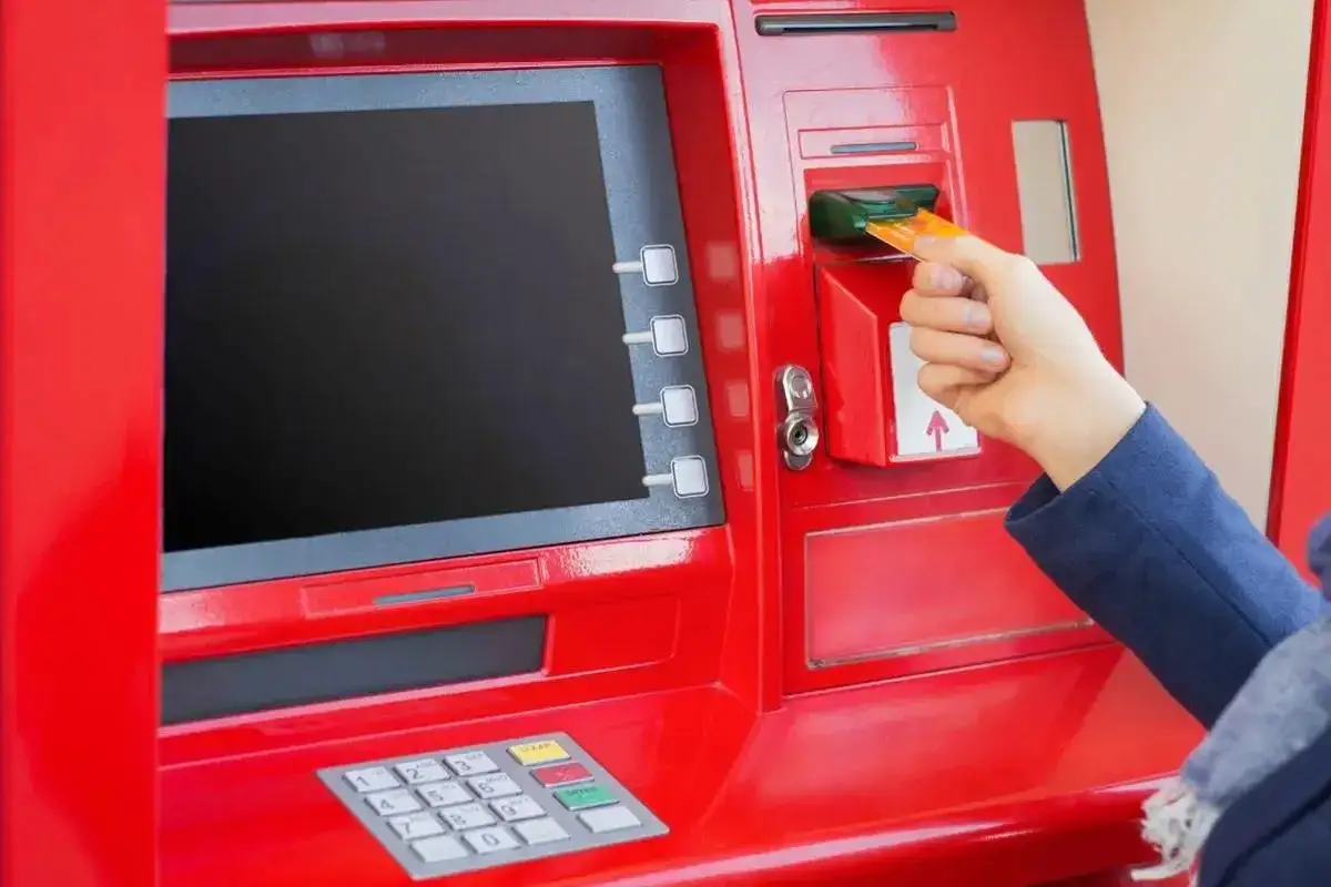 Ręka wkłada kartę do bankomatu. Planujesz podróż i zastanawiasz się, jaką walutę zabrać do Turcji?