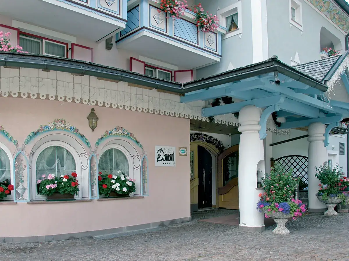 Ingresso decorato con fiori e affreschi al Park Hotel Diamant. L'architettura alpina è colorata e accogliente.
