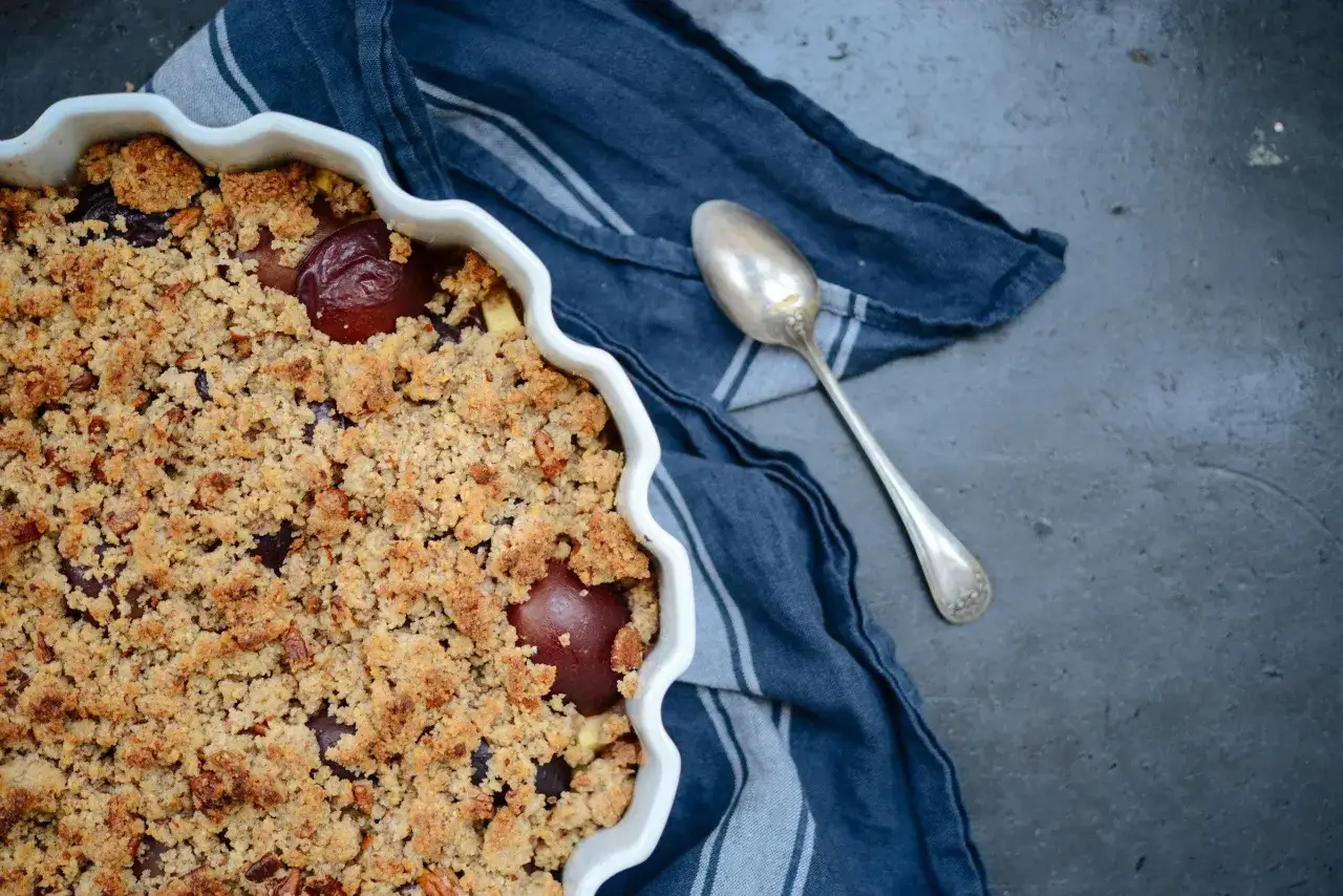 Un d&eacute;licieux crumble aux quetsches, pr&ecirc;t &agrave; &ecirc;tre d&eacute;gust&eacute;. La cuill&egrave;re attend patiemment.
